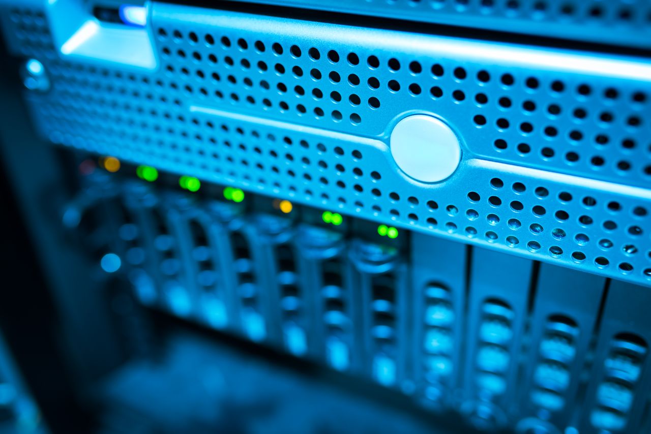 Home Focused view of a modern data server rack with blinking lights in a blue-lit environment.